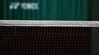 A badminton net, with a green curtain in the background.