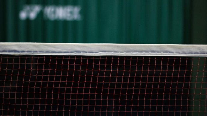 A badminton net, with a green curtain in the background.